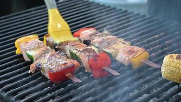 barbecue met zalm en gegrilde groenten. de kok smeert de kebab in met boter video