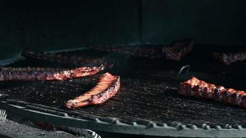 las costillas de cerdo dan vueltas en la parrilla. con humo y fuego. video