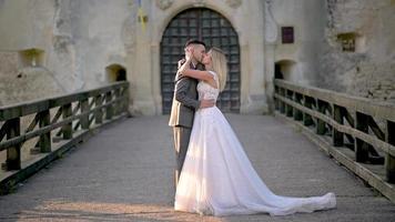 os noivos estão se beijando apaixonadamente no fundo do antigo castelo. video