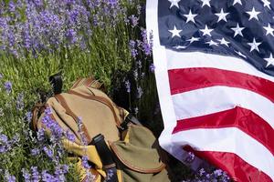 Tourist backpack and USA flag on lavender field, no people. photo