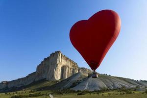 globo aerostático, globo rojo en forma de corazón volador contra el fondo de la roca blanca. foto