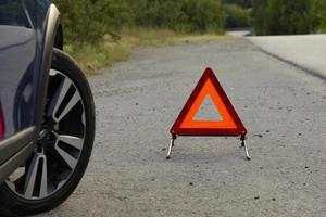 An emergency stop sign of a vehicle is installed on the road, next to the car. Copy space. photo