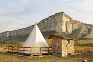 Great view of the tipi in the field with the American rocky mountain landscape in the background. photo