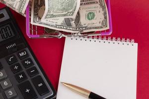 White notepad with calculator and stylish pen on a red background. Copy space. photo