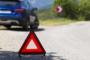 An emergency stop sign of a vehicle is installed on the road, next to the car. Copy space. photo