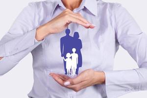 Family life insurance, family services and supporting families concepts. Businesswoman with protective gesture and silhouette representing young family. photo