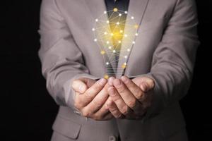 A businessman in a suit with a light bulb in his hands. Holds a glowing idea icon in his hand. With place for text. photo