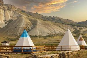 Great view of the tipi in the field with the American rocky mountain landscape in the background. photo