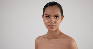 portrait de visage de femme asiatique heureuse regardant la caméra. beau modèle féminin avec une peau fraîche parfaite et propre. traitement de soins de la peau ou concept d'annonces cosmétiques. video