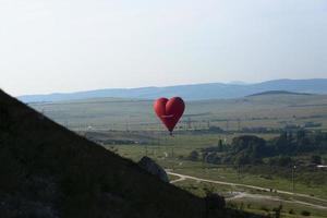 Hot air balloon, Red balloon in the shape of a flying heart against the background of the White Rock. photo