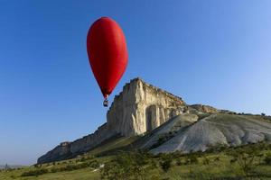 Hot air balloon, Red balloon in the shape of a flying heart against the background of the White Rock. photo