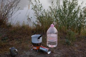 Picnic in nature. A gas burner and a mug of hot tea. photo