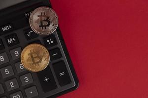 Calculator, Bitcoin coins on a red background. Copy space. photo