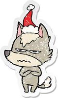 distressed sticker cartoon of a annoyed wolf wearing santa hat vector