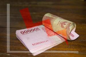 One hundred thousand rupiah with a red descending line chart photo