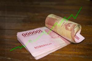 billete de cien mil rupias con diagrama de línea ascendente verde foto