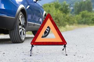 se instala una señal de parada de emergencia de un vehículo en la carretera, al lado del coche. copie el espacio foto