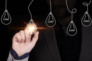Businessman hand touching glowing lightbulb among lamp does not light for selective creative smart thinking ideas and innovation concept. photo