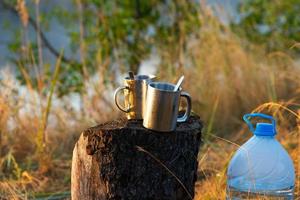picnic en la naturaleza. dos tazas térmicas de metal con cucharas se colocan sobre un tocón de árbol. foto