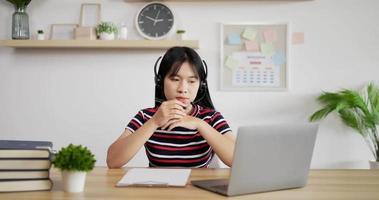 Portrait of Young Asian customer service support agent telemarketer wearing headset looking at laptop make business conference internet video call.