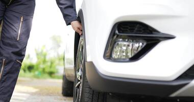 nahaufnahme eines asiatischen automechanikers, der während der fahrzeugwartung auf einer nebenstraße das rad abnehmen wird. junger Mann mit Schraubenschlüssel. Auto-Service-Konzept. video