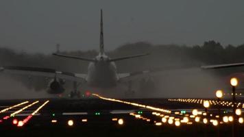 el avión de cuerpo ancho frenando después de aterrizar en la pista iluminada temprano en la mañana video