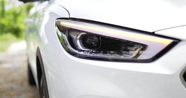 close-up da iluminação frontal do carro estacionado na estrada. faróis de carro piscando lâmpada led. video