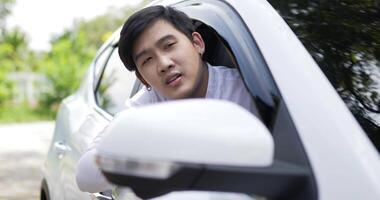 Portrait of Angry Asian man sitting behind the wheel of a car and complaining about traffic. Male sitting in car bored with traffic, sticking out of the car. video