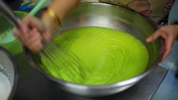 com um liquidificador de imersão com um batedor, a garota bate a massa em uma panela de metal. o processo de fazer uma massa para assar em casa. cozinhar torta, biscoitos, pizza em casa na cozinha. video