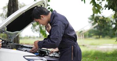 portrait d'une jeune femme asiatique et d'un mécanicien ouvrant le capot d'une voiture sur une route secondaire. concept de service de voiture. video