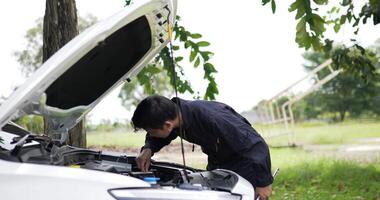 aziatische man monteur inspectie schijnt een toorts automotor controleren bug in motor. serviceonderhoudsverzekering met automotor. auto dienstverleningsconcept. video