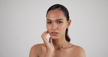 close-up do rosto de mulher asiática atraente, olhando para a câmera. bela modelo feminino com pele fresca limpa perfeita. tratamento de cuidados com a pele ou conceito de anúncios cosméticos. video