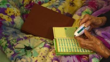 Elderly woman at home use electric Koran read pen to read in arabic video