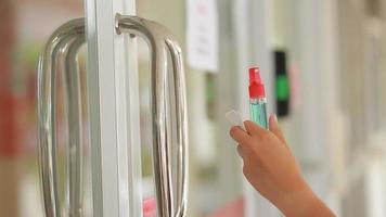 Hand of woman is spraying alcohol,disinfectant on workplace door for safety,prevent infection of Covid-19 virus,contamination of germs or bacteria,wipe clean surfaces that are frequently touched. video