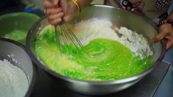 With an immersion blender with a whisk, the girl beats dough in a metal pot. The process of making a dough for home baking. Cooking pie, cookies, pizza at home in the kitchen. video