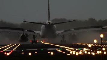 The wide bodied aircraft braking after landing on the illuminated runway in the early morning video