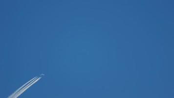 Contrails in the blue sky. Airplane flying high. Slow motion video
