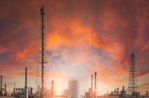 Oil refinery or petroleum refinery plant with red sunset sky background. Power and energy industry. Oil and gas production plant. Petrochemical industry. Natural gas storage tank. Petroleum business. photo