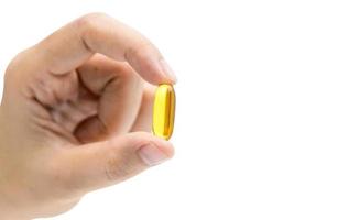 Asian woman hand holding yellow capsule pills isolated on white background. Take pills. Vitamin and supplements concept. Healthy life. Fish oil capsule pills. Omega 3 supplements. Food supplements. photo
