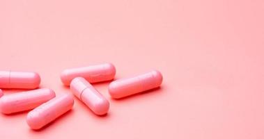 píldora de cápsulas de color rosa sobre fondo de color rosa. vitaminas y suplementos. farmacia en línea. pancarta de la tienda de farmacia. industria farmacéutica. concepto de seguro de salud de la mujer. Pastillas para el amor y la vida feliz. foto