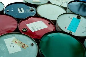 Old chemical barrels. Blue, green, and red oil drum. Steel oil tank. Toxic waste warehouse. Hazard chemical barrel with warning label. Industrial waste in drum. Hazard waste storage in factory. photo