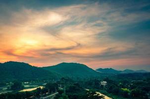 Beautiful nature landscape of mountain range with sunrise sky and clouds. City in mountain valley in Thailand. Scenery of mountain layer with morning sunrise. Tropical forest. Nature background. photo