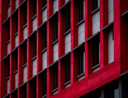 Glass window of skyscraper office building with red and white concrete wall. Exterior commercial building. Modern architecture design. Facade of modern business building. Concrete and glass building. photo