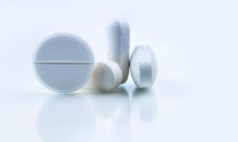 Round and oval white tablets pills on whit background. Selective focus on white tablets pills. Pharmaceutical industry. Drug production. Pharmacy drugstore products. Pharmaceutical manufacturing.