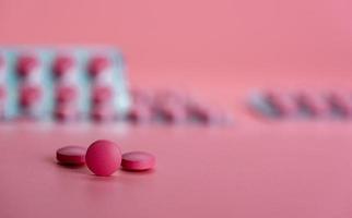 Round pink tablet pill on blur blister pack. Prescription drug. Painkiller or antibiotic tablet pill on pink background. Pharmaceutical industry. Health and wellbeing background. Pharmaceutics concept photo