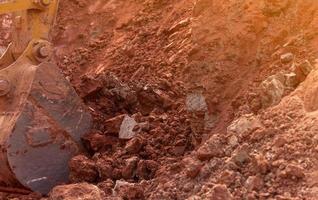 Backhoe working by digging soil at construction site. Bucket of backhoe digging soil. Crawler excavator digging on dirt. Closeup backhoe bucket of yellow backhoe. Earthmoving. Trenching machine. photo