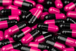 Pile of pink-black capsule pills. Antibiotics resistance. Drug use with reasonable. Global healthcare concept. Antibiotics drug resistance. Antimicrobial capsule pills. Pharmaceutical industry. photo