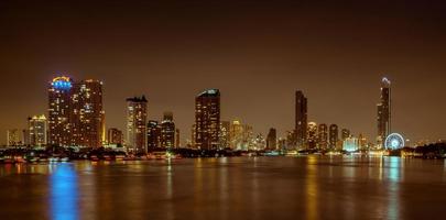 paisaje urbano de edificio moderno cerca del río en la noche. edificio de oficinas de arquitectura moderna. rascacielos con cielo de noche. fotografía nocturna del edificio frente al río. condominio luz abierta en la noche. foto