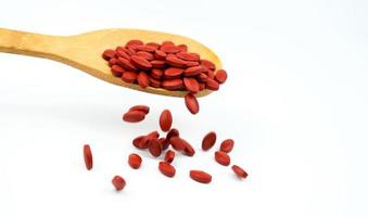 Iron tablets in spoon falling on white background. Ferrous fumarate for treatment anemia in adult, elderly people and children. Blood donations concept. Red tablets pills on wooden spoon. Pharmacy photo