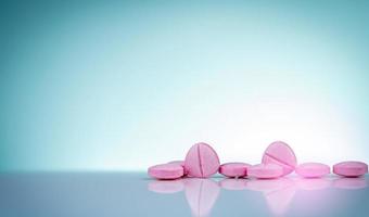 Pink tablets pills with shadow on gradient background. Pharmaceutical industry. Pharmacy products. Vitamins and supplements. Medication use in hospital or drugstore. Global drug retail market. photo